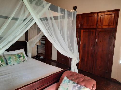 a bedroom with a canopy bed and a chair at St. Lucia Wetlands Guest House in St Lucia