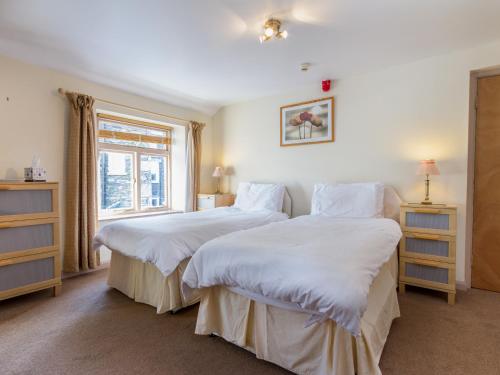 two beds in a room with a window at Elim House - Adults Only in Bowness-on-Windermere