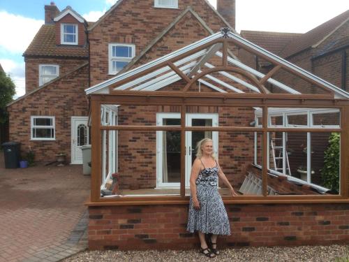 a woman standing in front of a glass greenhouse at Laurel Lodge in Horncastle