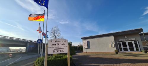a hotel sign in front of a building with a flag at Hotel zur Riede bei Bremen in Delmenhorst