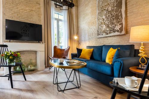 - un salon avec un canapé bleu et un mur en briques dans l'établissement Casa Sevilla 1855 Suites by Época, à Séville