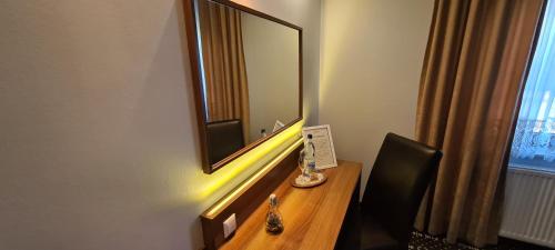 a room with a desk with a mirror and a chair at Hotel zur Riede bei Bremen in Delmenhorst