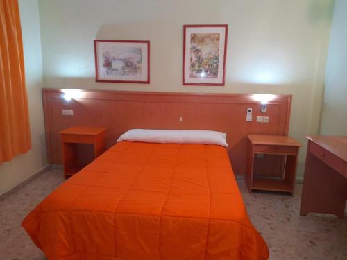a bedroom with a bed with an orange blanket at Hostal Carlos III in El Ejido