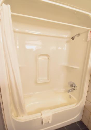 a white bath tub with a shower curtain in a bathroom at Canad Inns Destination Centre Transcona in Winnipeg
