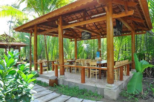 a wooden pavilion with wooden tables and chairs at Ben Tre Farm Stay in Ben Tre