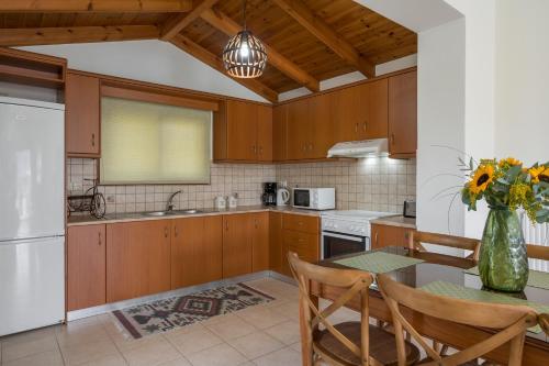 una cocina con armarios de madera y una mesa con un jarrón de flores en Bluefairy Villas, en Kávallos