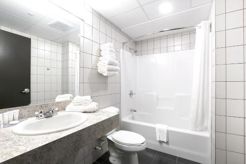 Canad Inns Destination Centre Transcona في وينيبيغ: حمام مع حوض ومرحاض وحوض استحمام