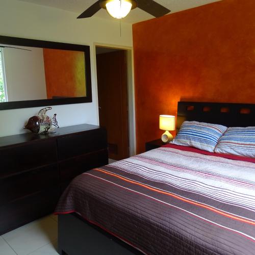 a bedroom with a large bed with a red wall at 3Room Jaco Condos in Jacó
