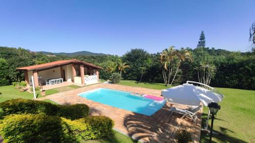 una piscina in un cortile con una casa di PARAÍSO ECOLÓGICO- REGIÃO ATIBAIA a San Paolo