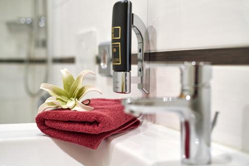 ein rotes Handtuch auf einem Waschbecken neben einem Wasserhahn. in der Unterkunft Hotelgasthof zur Sonne in Bad Gögging