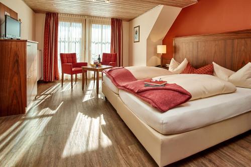 ein Schlafzimmer mit einem großen Bett, einem Tisch und Stühlen in der Unterkunft Hotelgasthof zur Sonne in Bad Gögging