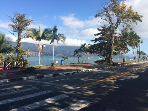 eine leere Straße mit Palmen und dem Meer in der Unterkunft Casa a 100mts da praia in Ilhabela