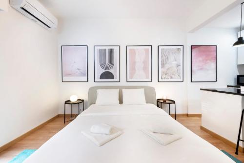 um quarto com uma grande cama branca com quatro quadros na parede em Yolo Apartment by Olala Homes em Cascais