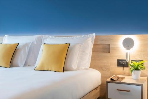 a bedroom with a white bed with yellow pillows at Antoniel Suites in St Julian's