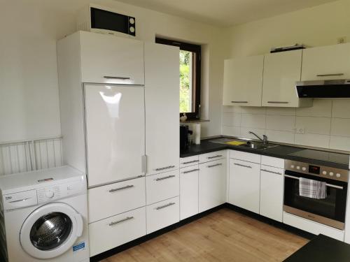 cocina con armarios blancos y lavadora en Ferienhaus Nele en Hilders