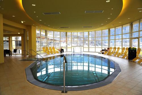 ein großer Pool in einem Gebäude mit Stühlen in der Unterkunft Gesundheitsresort Bad St. Leonhard in Bad Sankt Leonhard im Lavanttal