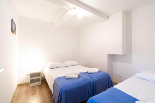 a white bedroom with two beds and a blue blanket at Apartamenty Poddąbek- basen kryty, sauna, animacje dla dzieci , małpi gaj, baseny na dachu in Poddąbie