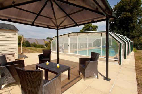 un patio avec une table et des chaises sous un parasol dans l'établissement Stone cottage with modern cosy interior near to Josselin Perfect retreat for Writers or Star Gazers, à Guégon