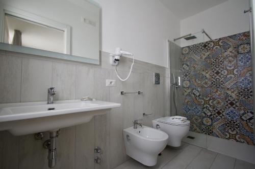 a bathroom with a sink and a toilet and a mirror at La Guitgia Rooms in Lampedusa