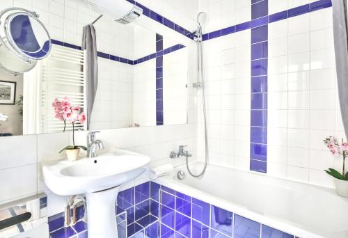 y baño con azulejos azules y blancos, lavabo y bañera. en 834 - Spacious flat in Paris Olympic Games 2024, en París