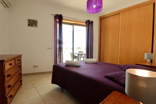 - une chambre avec un lit violet et une fenêtre dans l'établissement Olhos De Água 1BR with Pool, AC and Free Parking, à Albufeira