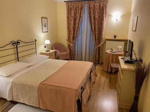 a hotel room with a bed and a desk and curtains at LA SISMONDA in Rodello