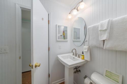 Baño blanco con lavabo y espejo en Forever Summer en Tybee Island
