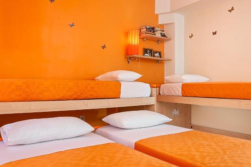 three beds in a room with orange walls at Cretan Blu Platanias in Plataniás