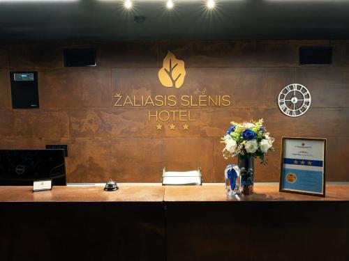 eine Hotellobby mit einer Rezeption mit Blumen darauf in der Unterkunft Zaliasis slenis - Self check-in hotel - Free parking in Klaipėda