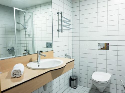 a bathroom with a sink and a toilet at Zaliasis slenis - Self check-in hotel in Klaipėda