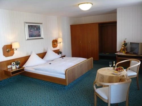 una camera d'albergo con un grande letto e un tavolo di Hotel Strauss a Hof