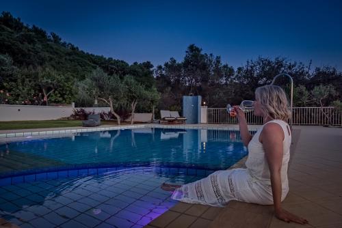 a woman sitting next to a pool taking a picture at Cretan Blu Platanias in Plataniás