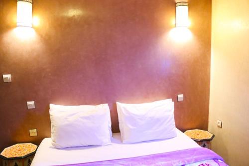 a bedroom with a bed with two pillows and two lights at Dar Diafa Kaltom in Ouzoud