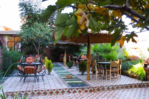 a patio with tables and chairs and an umbrella at Dar Diafa Kaltom in Ouzoud