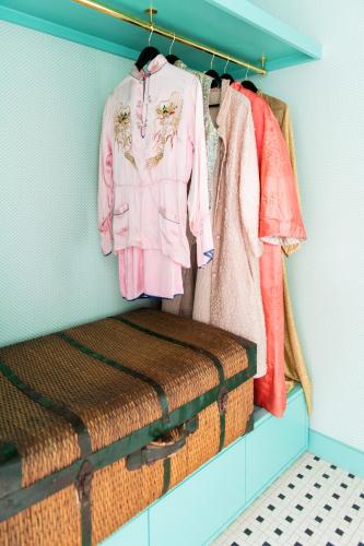 a rack of clothes and a pink shirt and a suitcase at Bradford House, a Member of Design Hotels in Oklahoma City
