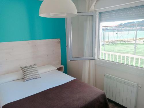 ein Schlafzimmer mit einem Bett und einem großen Fenster in der Unterkunft Apartamentos Rodeiramar 2A in Cangas