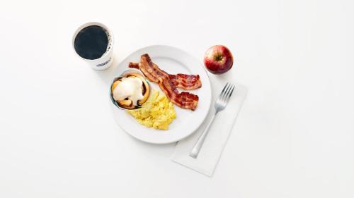 a plate of breakfast food with bacon and eggs and a cup of coffee at Holiday Inn & Suites Virginia Beach - North Beach by IHG in Virginia Beach