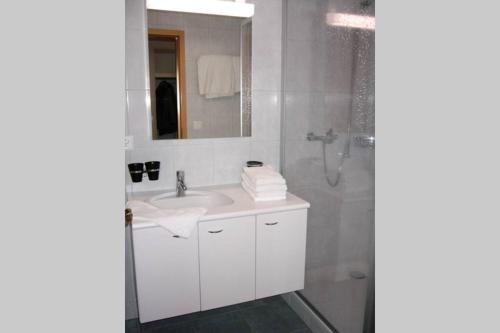 a white bathroom with a sink and a shower at Catherina 42 in Leukerbad