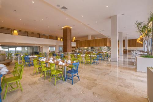 a restaurant with tables and chairs in a building at Sensira Resort & Spa Riviera Maya All Inclusive in Puerto Morelos