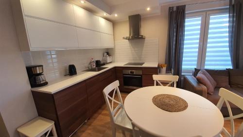 a kitchen and living room with a white table and chairs at Apartamenty Waterline Ustronie Morskie in Ustronie Morskie