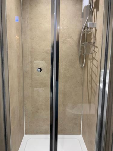 a shower with a glass door in a bathroom at Royal Snug & Wee Snug in Kincardine OʼNeil