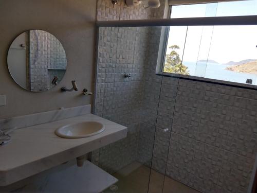 ein Bad mit einem Waschbecken, einem Spiegel und einer Dusche in der Unterkunft Panoramica Residencial in Barequeçaba