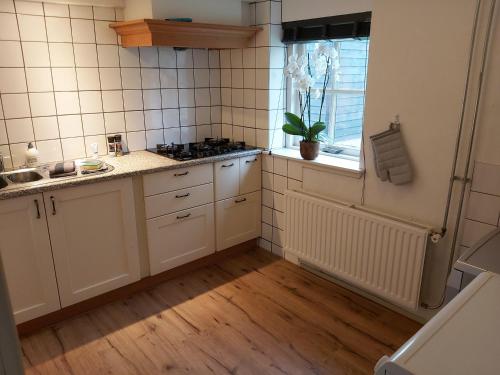 cocina con armarios blancos, fregadero y ventana en De Hammerhoeve en Dalfsen