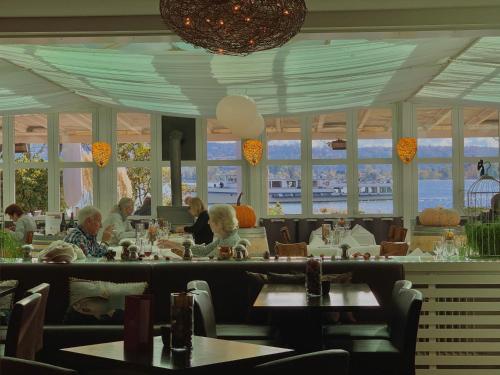 un grupo de personas sentadas en un restaurante con mesas en Hotel Jean-Jacques Rousseau en La Neuveville