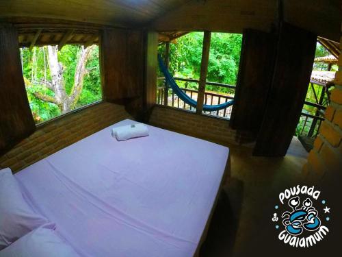 a small room with a bed and two windows at Pousada Guaiamum in Itacaré
