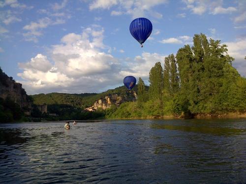 two hot air balloons flying over a river at Cottage de La Mothe in Marnac