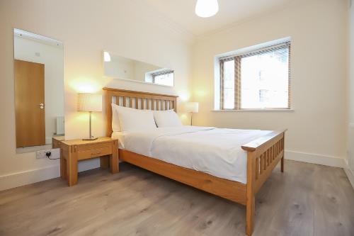 um quarto com uma cama grande, uma mesa de cabeceira e uma janela em IFSC Townhouse Apartments em Dublin