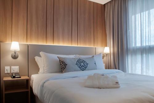a bedroom with a large white bed with a window at Exclusive Gramado Hotel & Spa by Gramado Parks in Gramado