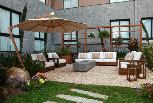 a patio with an umbrella and couches and chairs at Exclusive Gramado Hotel & Spa by Gramado Parks in Gramado