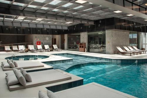 a large swimming pool with lounge chairs in a building at Exclusive Gramado Hotel & Spa by Gramado Parks in Gramado